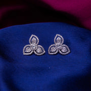 A pair of sterling silver stud earrings with an embellished leaflet design, displayed on a blue fabric.